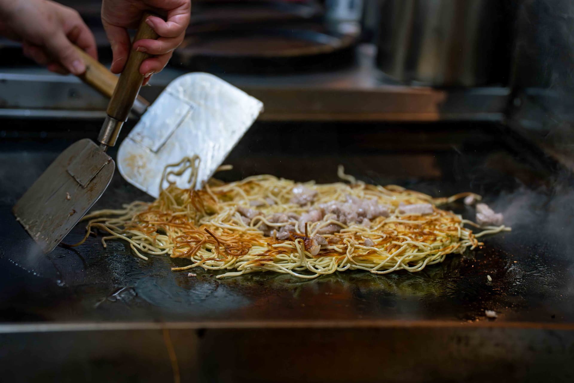 Yakisoba being grilled on an iron griddle