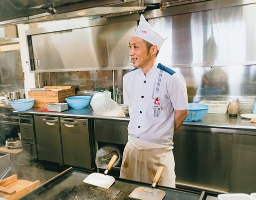 厨房で調理するK.Tさん